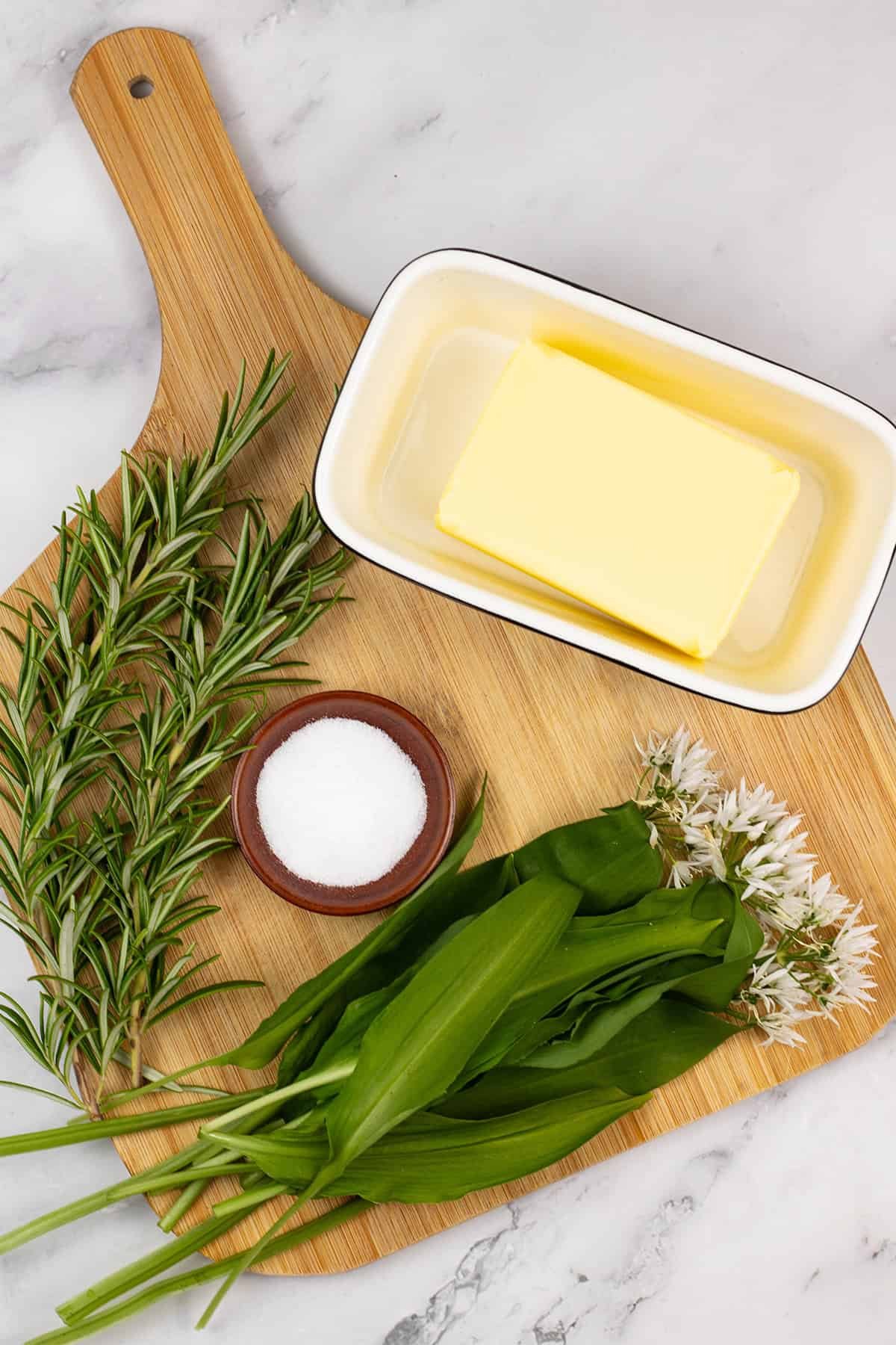 The ingredients for wild garlic and rosemary butter on a board.