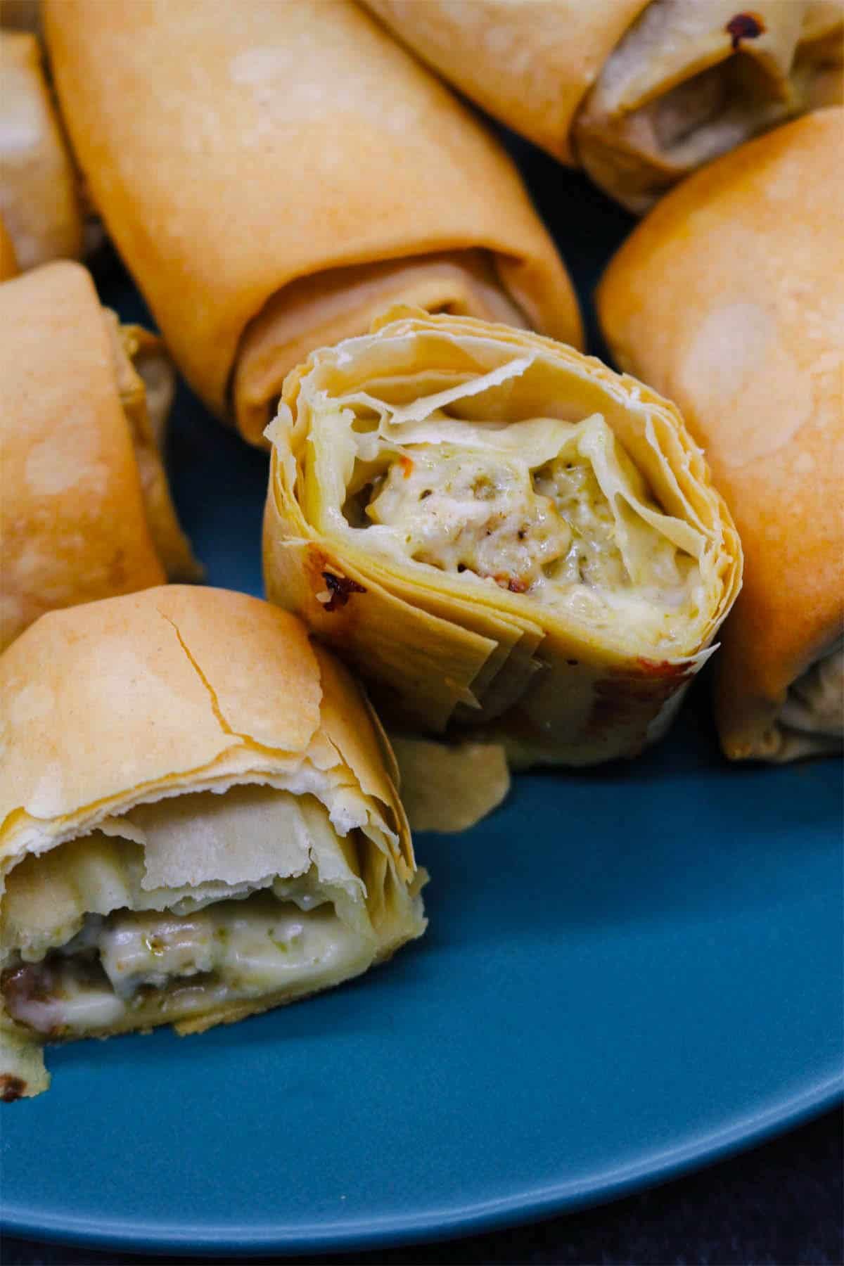 Chicken, mozzarella and pesto filo parcels on a teal dinner plate.