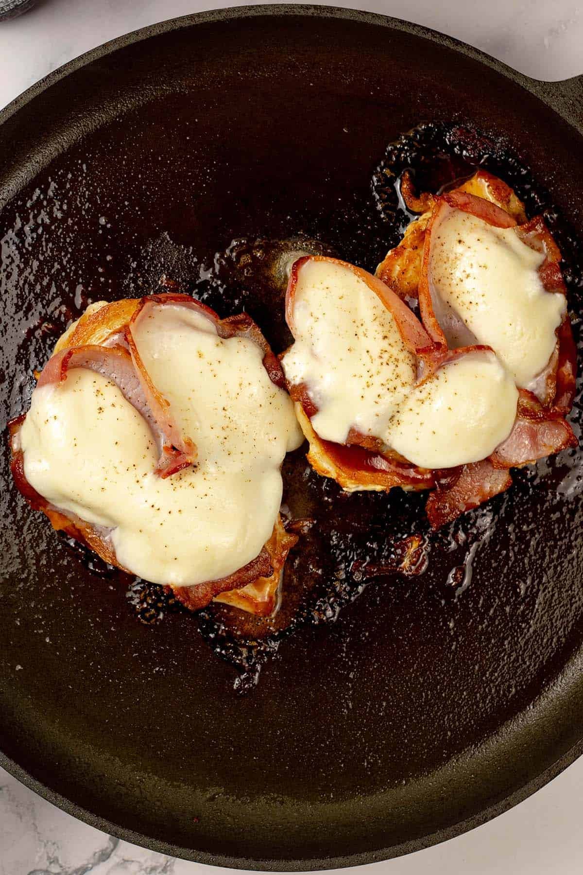 Two portions of smothered chicken in a large frying pan.