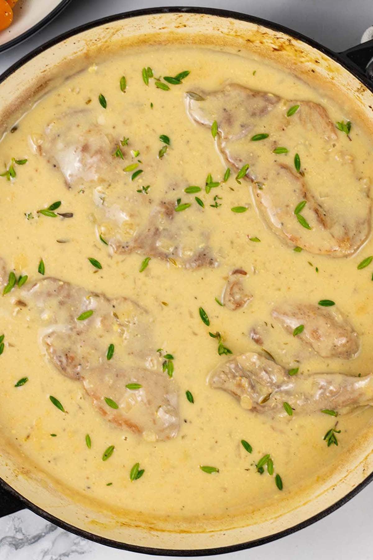 Braised pork steaks with mustard cream sauce in a shallow casserole.