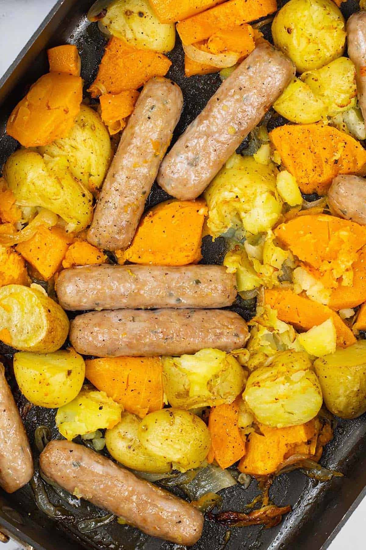 Sausage, squash and potato bake in a large roasting tin.