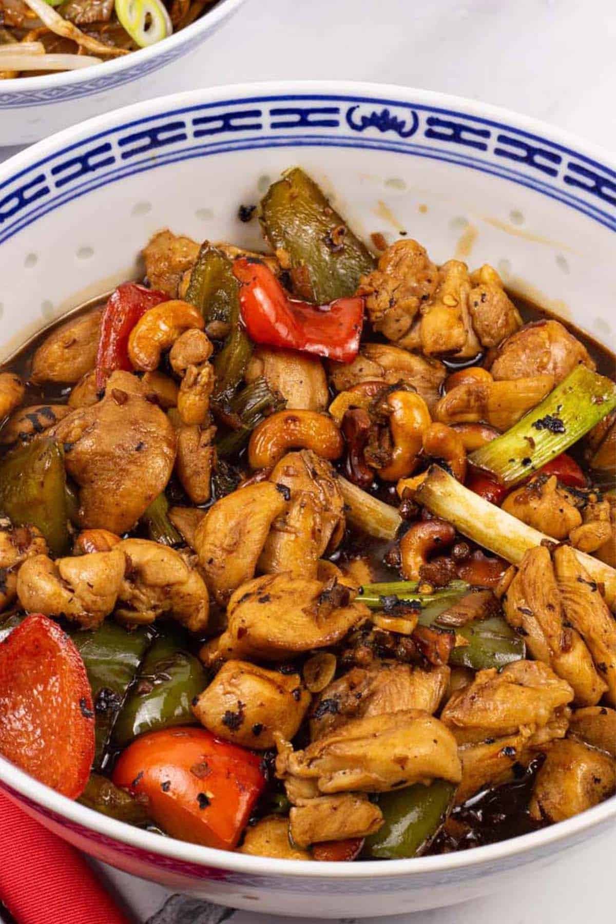 Kung pao chicken in a large blue and white oriental serving bowl.