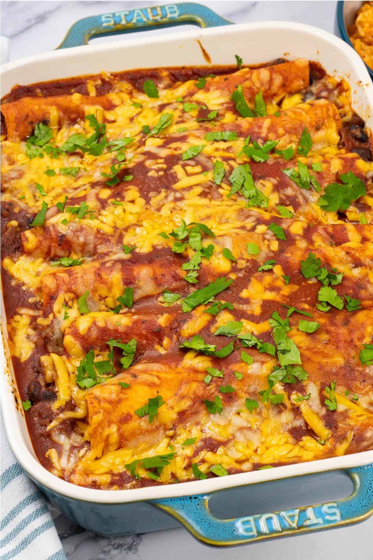 Beef and bean enchiladas in a rectangle Staub ovenproof dish.