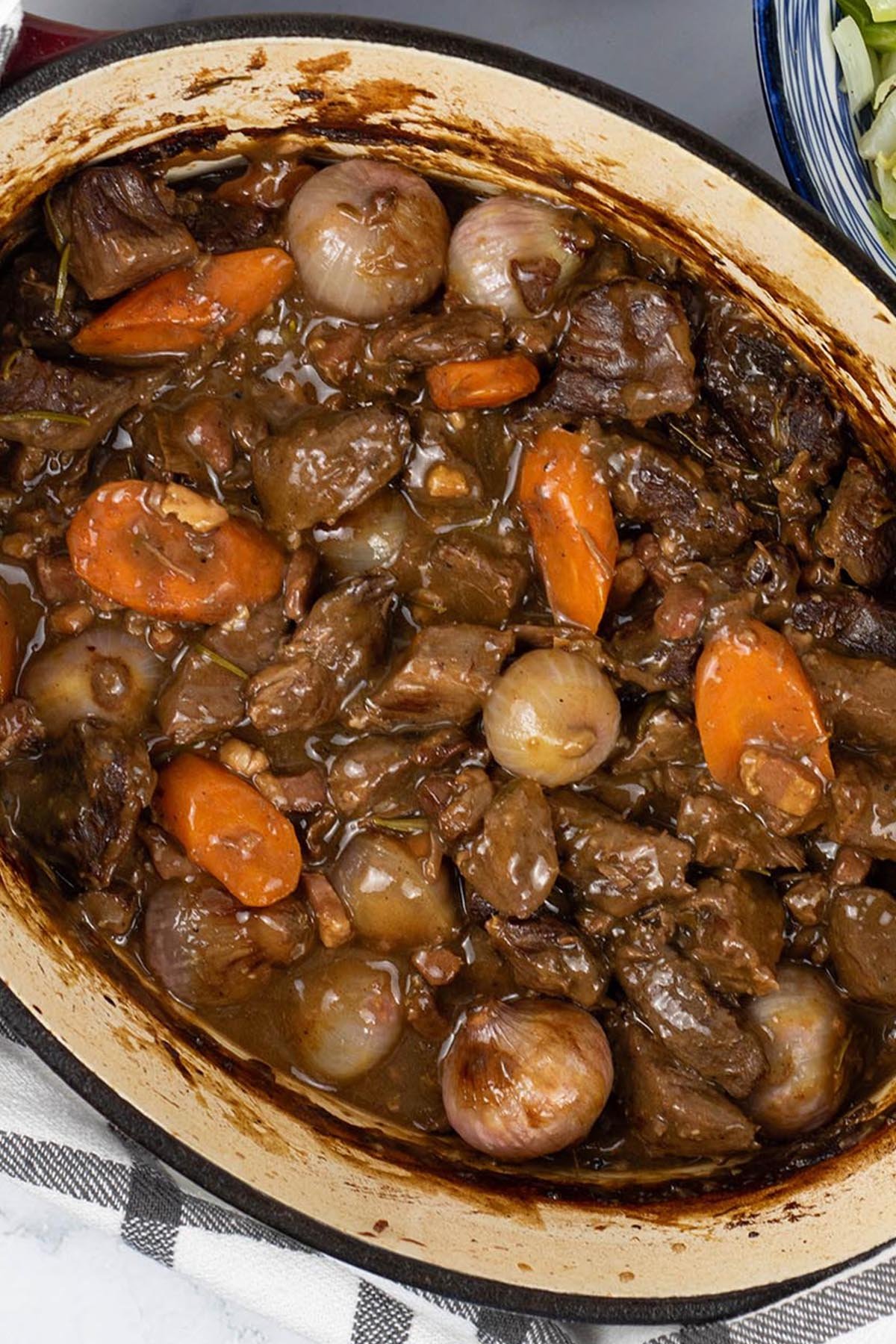 Close up photo of beef bourguignon in a deep oval casserole dish.