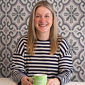 Deborah sitting at the breakfast bar in their kitchen with a green Head Chef mug.
