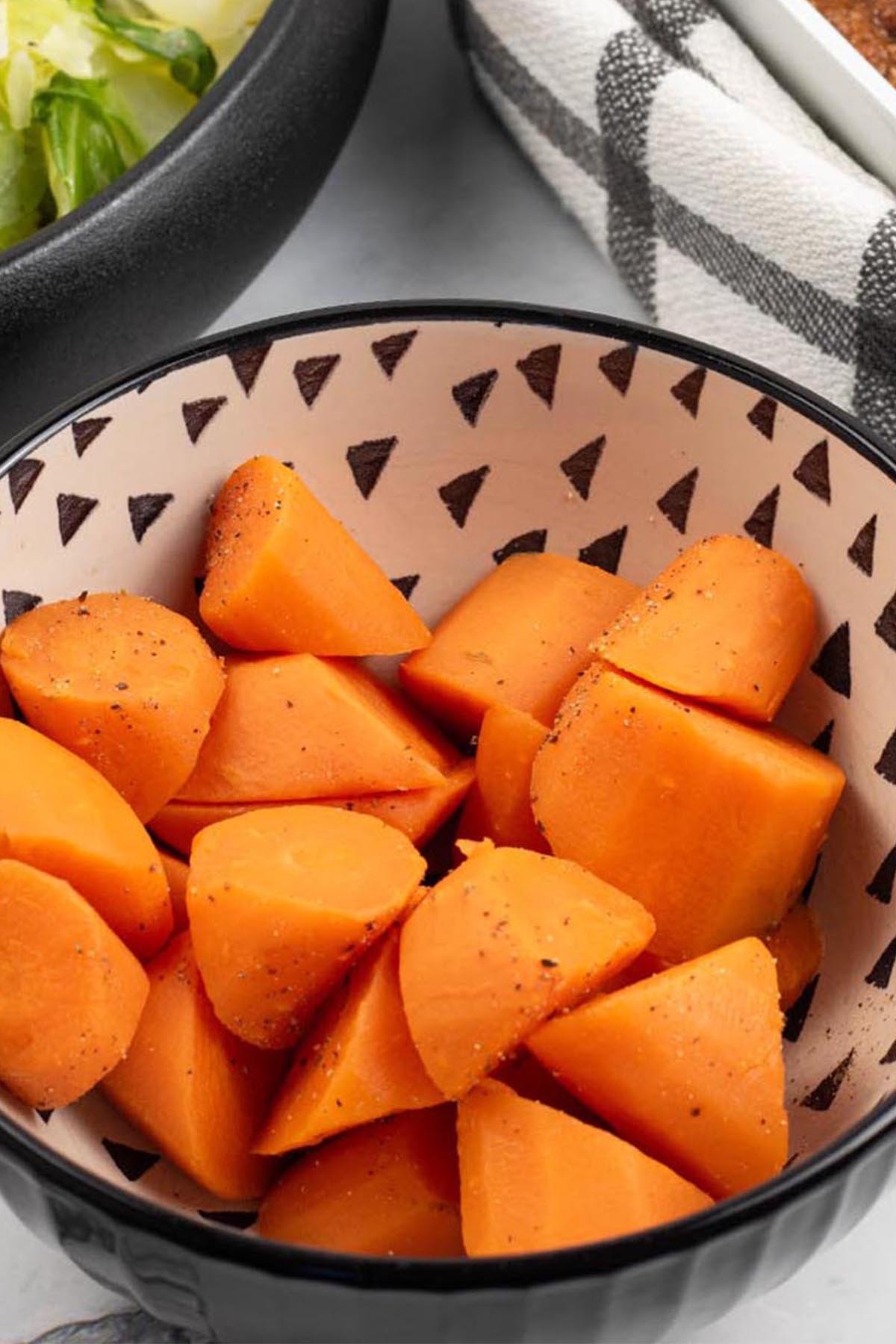 Close up photo of quick cook carrots in a black and cream patterned serving bowl.