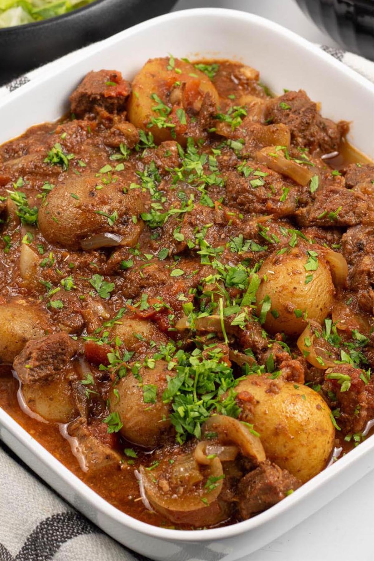 Slow cooker lamb stew with potatoes in a white square serving dish.