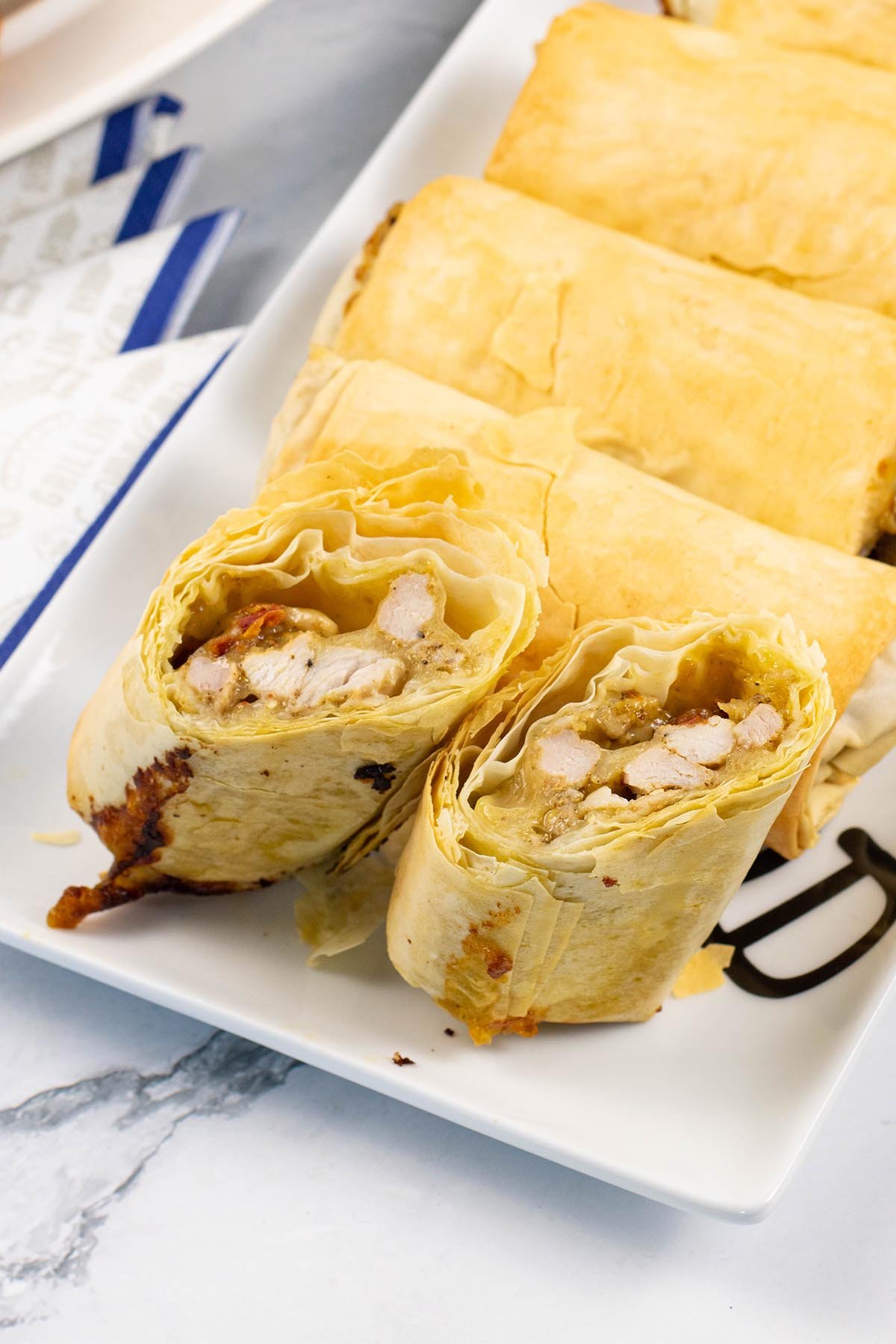 Chicken, mozzarella and pesto filo parcels on a white rectangular serving platter.