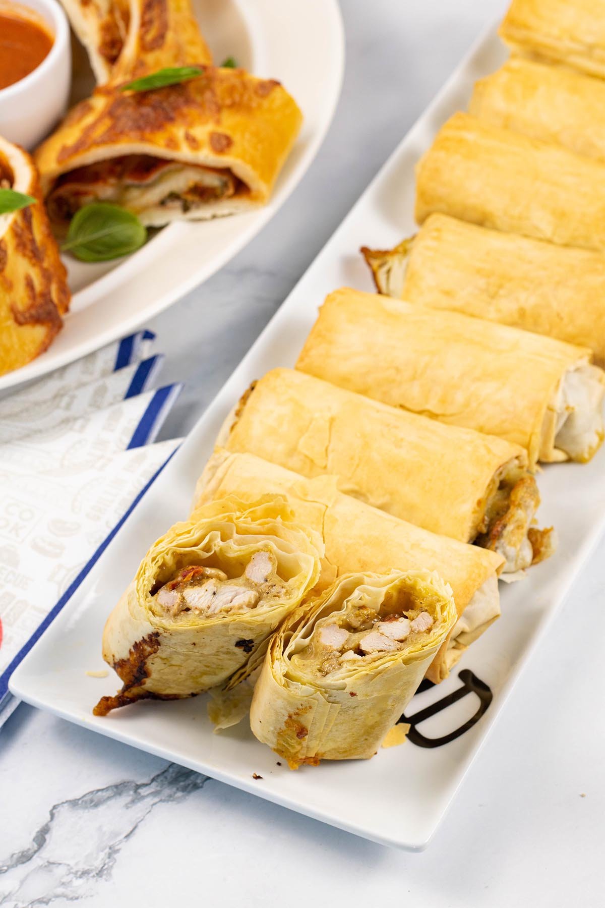 Chicken, mozzarella and pesto filo parcels on a white rectangular serving platter.