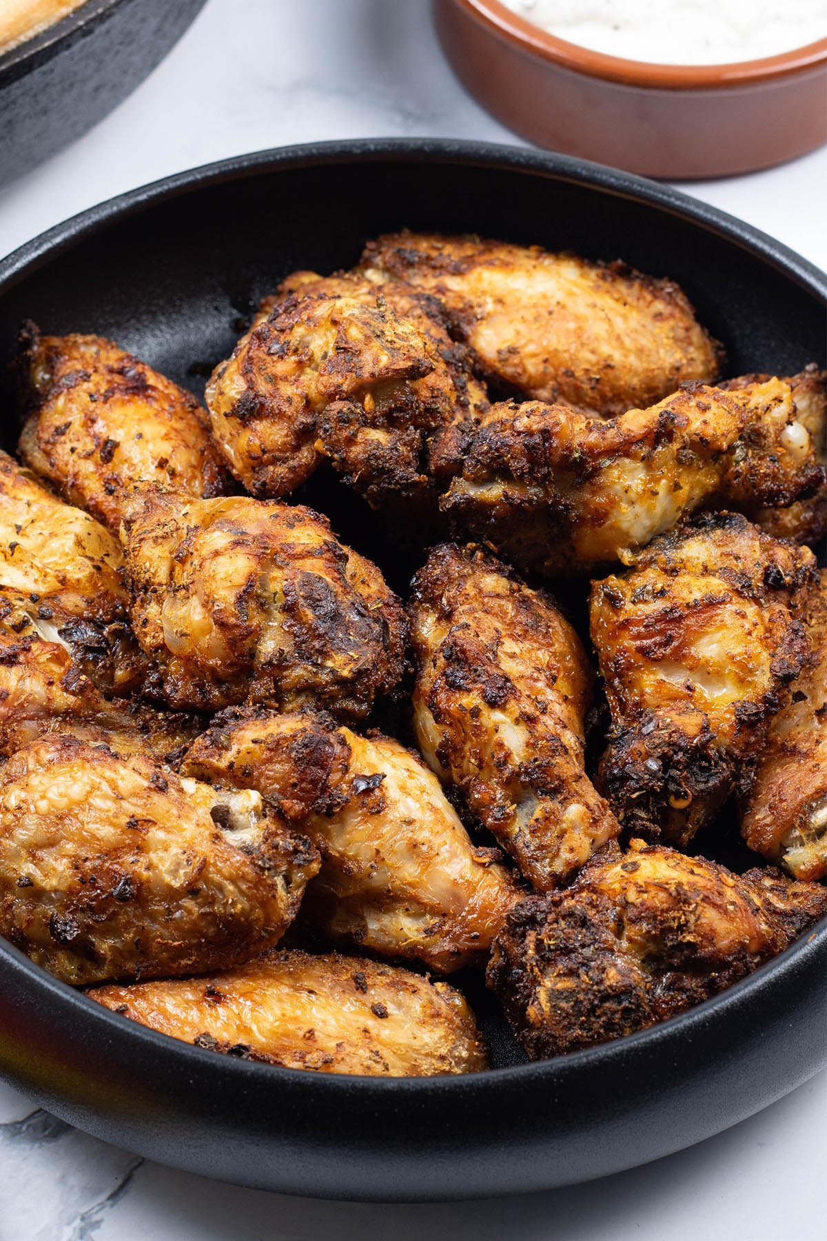 Easy air fryer Spanish chicken wings in a black serving bowl.