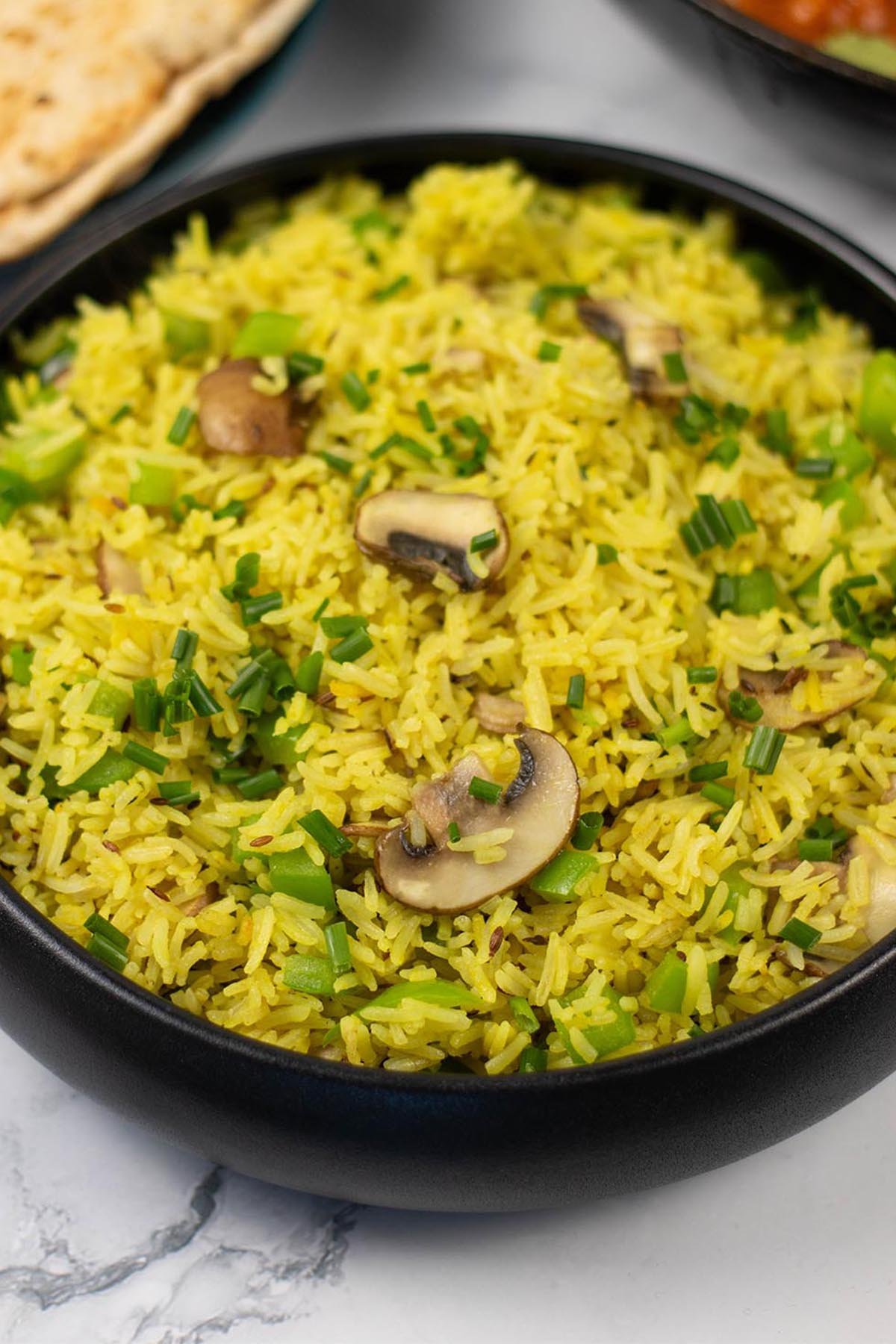 Close up of mushroom rice in a black serving bowl.