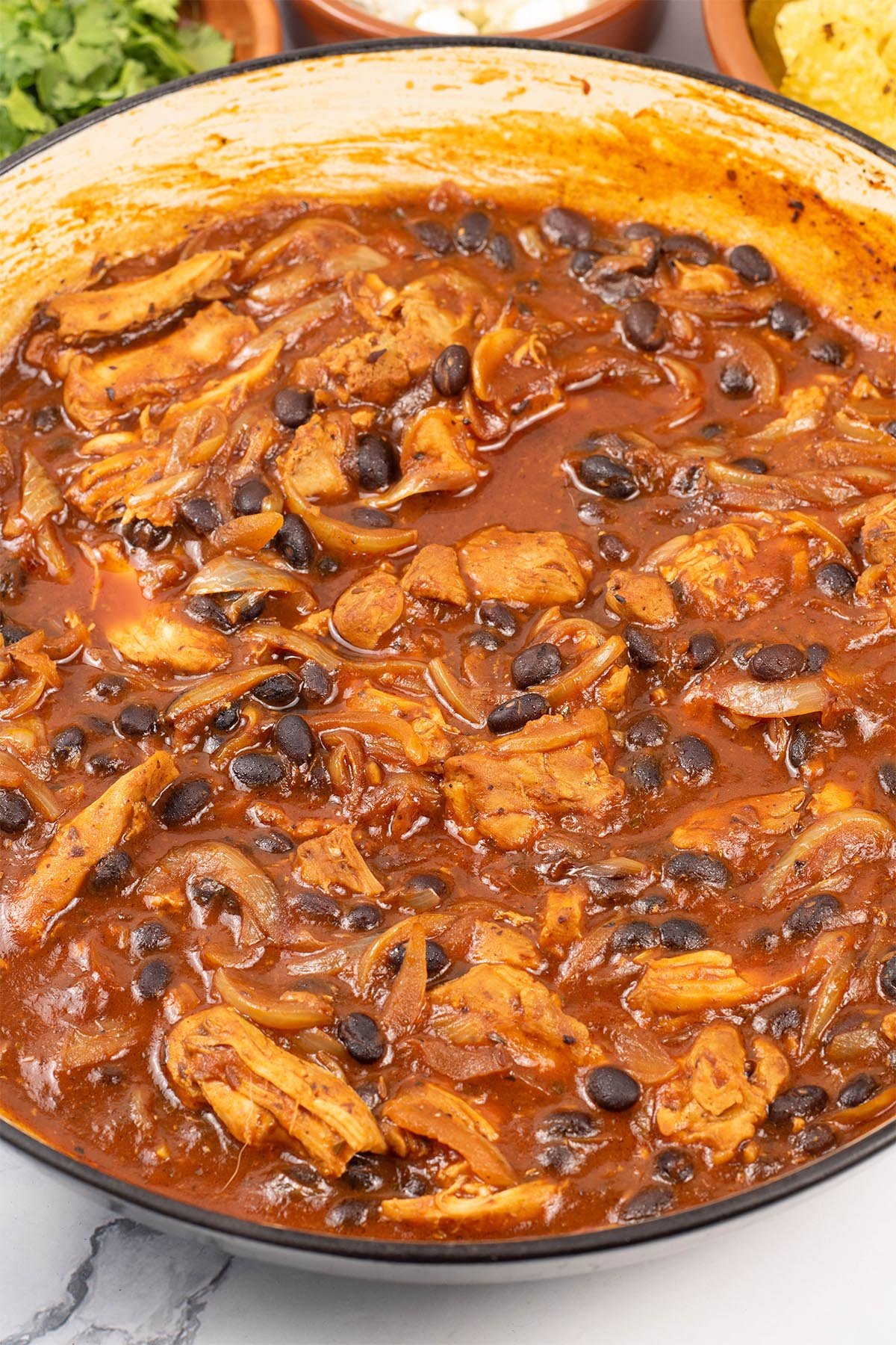 Pulled chicken and black bean chilli in a large round shallow casserole dish.
