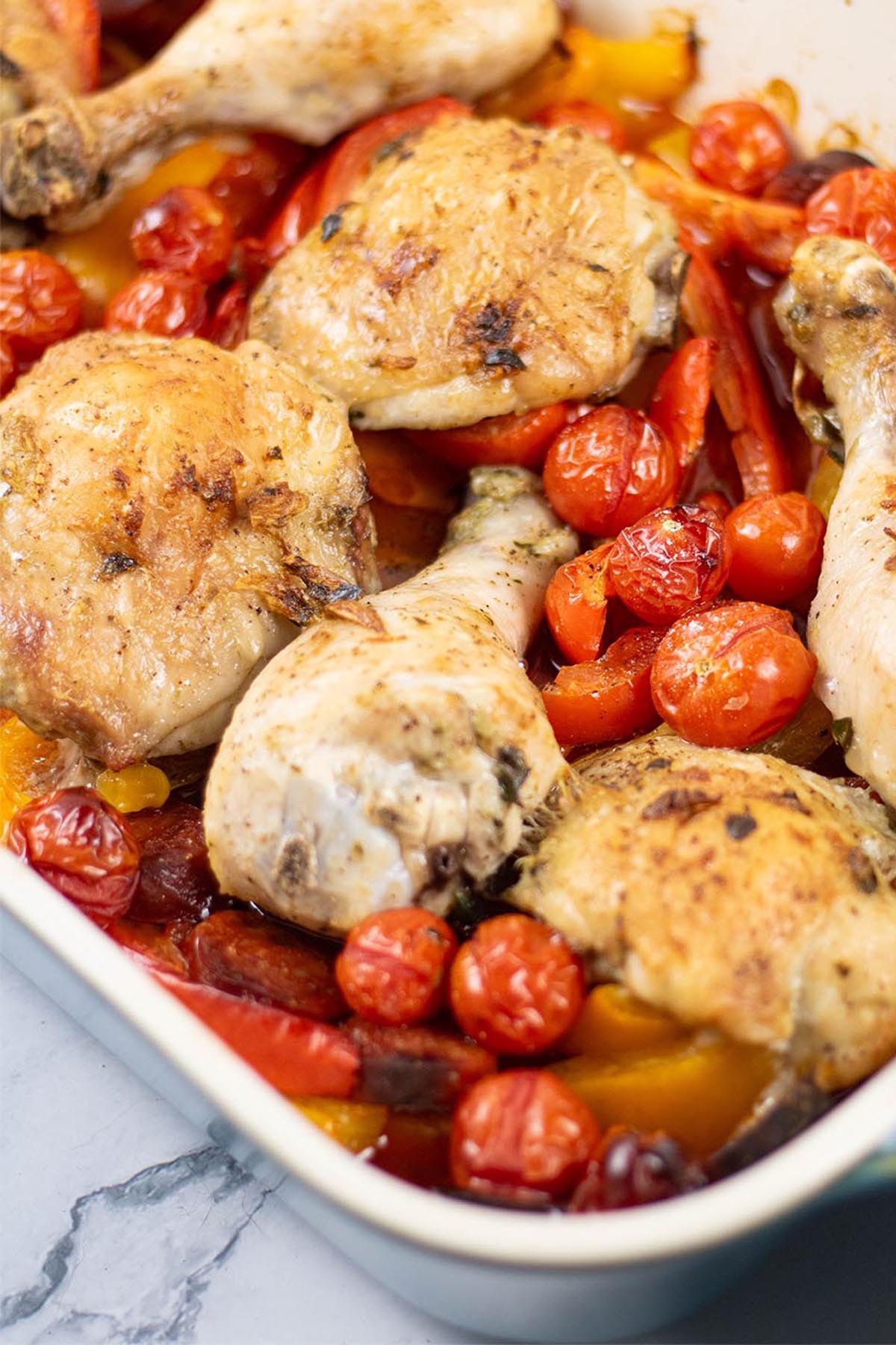 Close up photo of Spanish chicken tray bake in a large rectangle Staub oven dish.