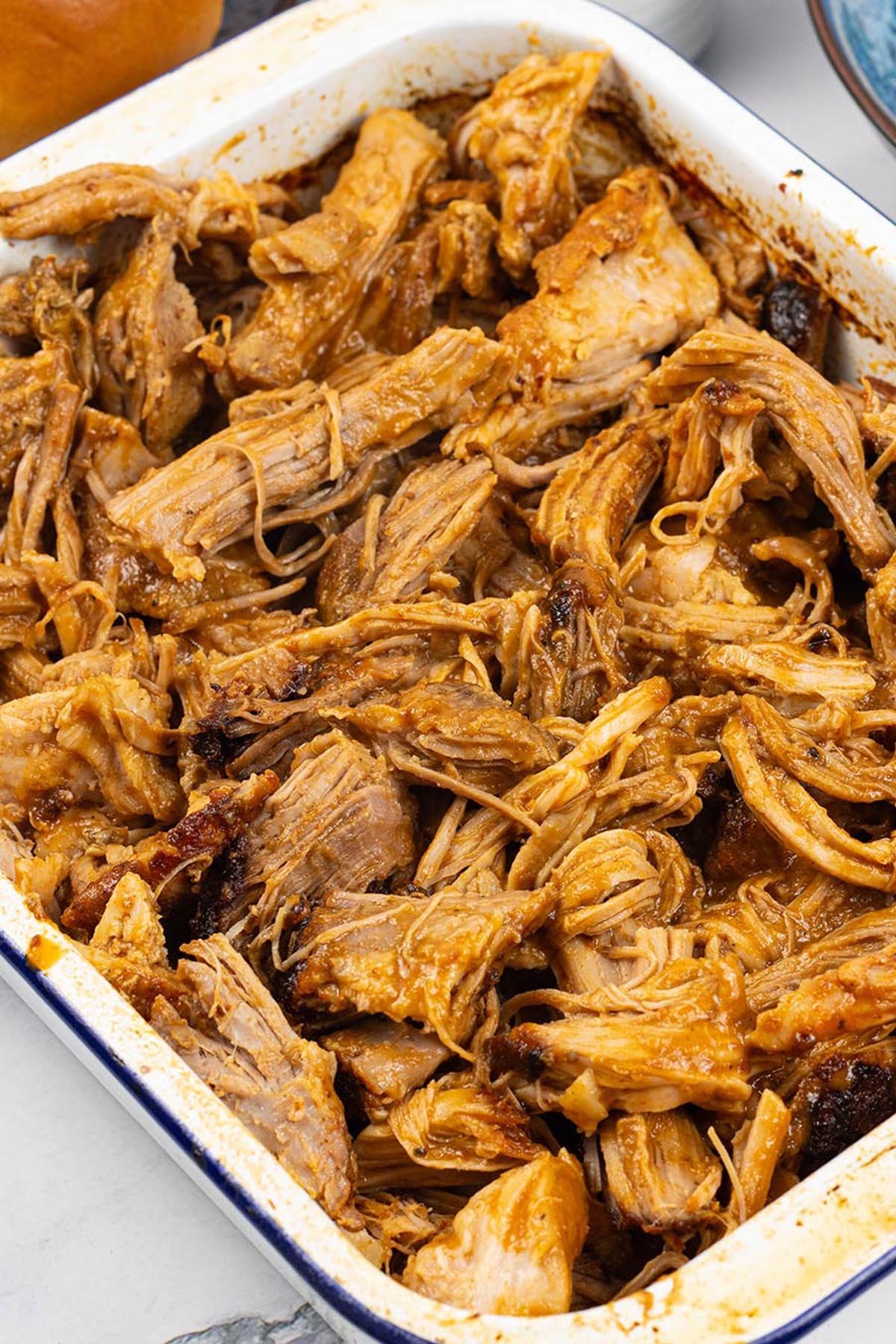 BBQ pulled pork in a blue rimmed white rectangle enamel roasting tin.