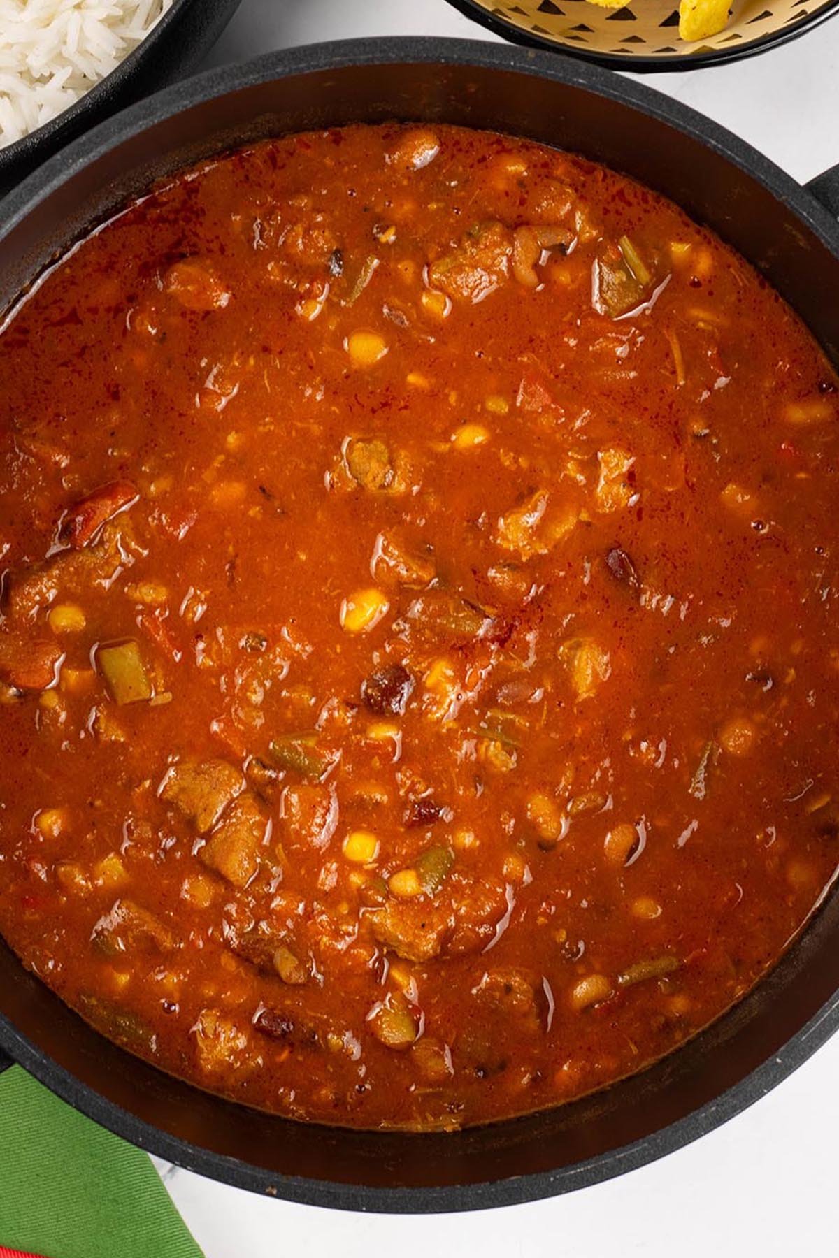 Close up of smoky pork and beans made in the Thermomix in a black casserole pot.