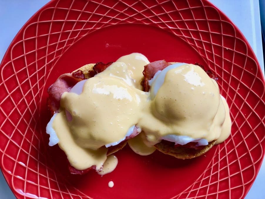 Eggs benedict and quick hollandaise on a red dinner plate