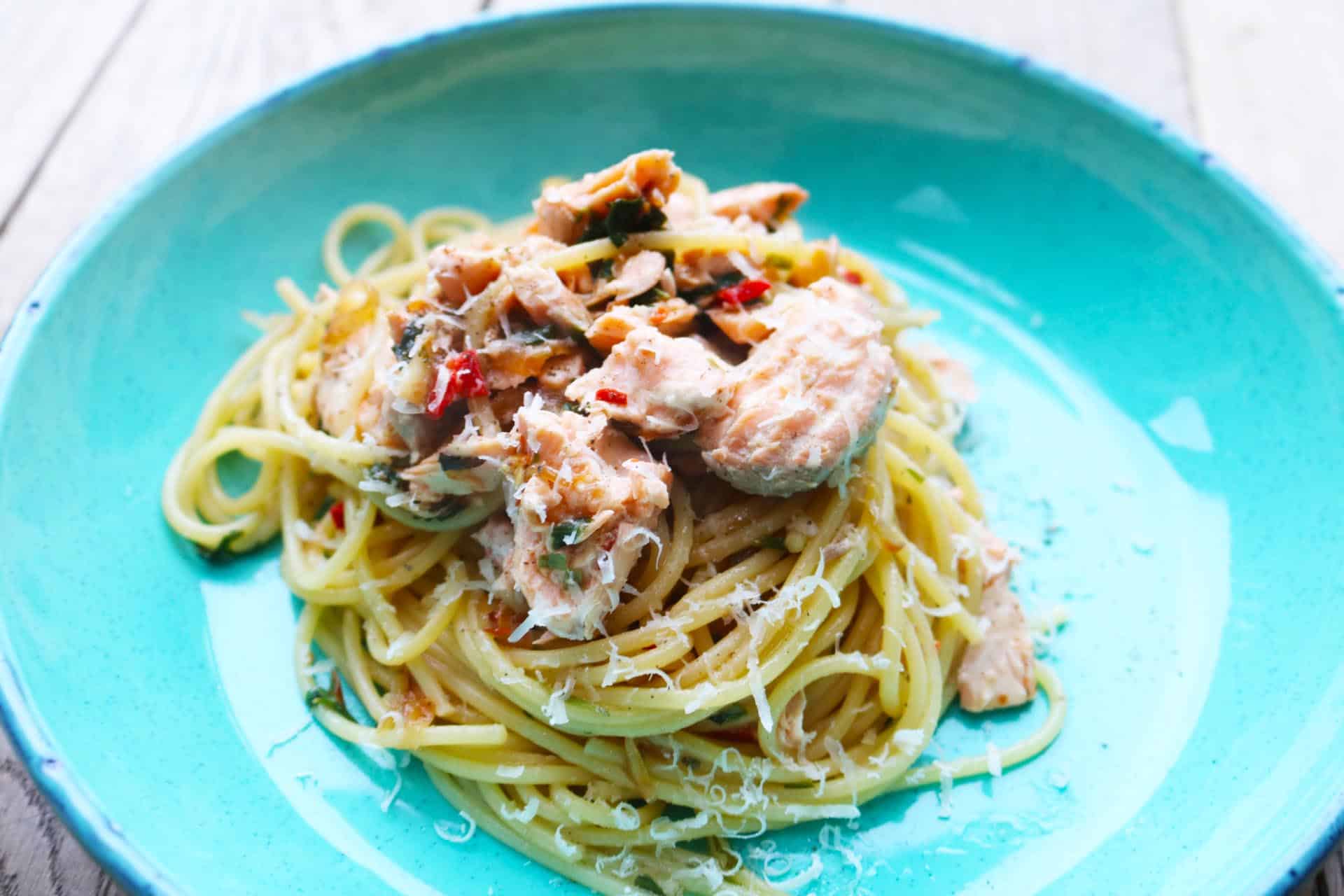 Spaghetti and salmon served in a turquoise blue pasta bowl