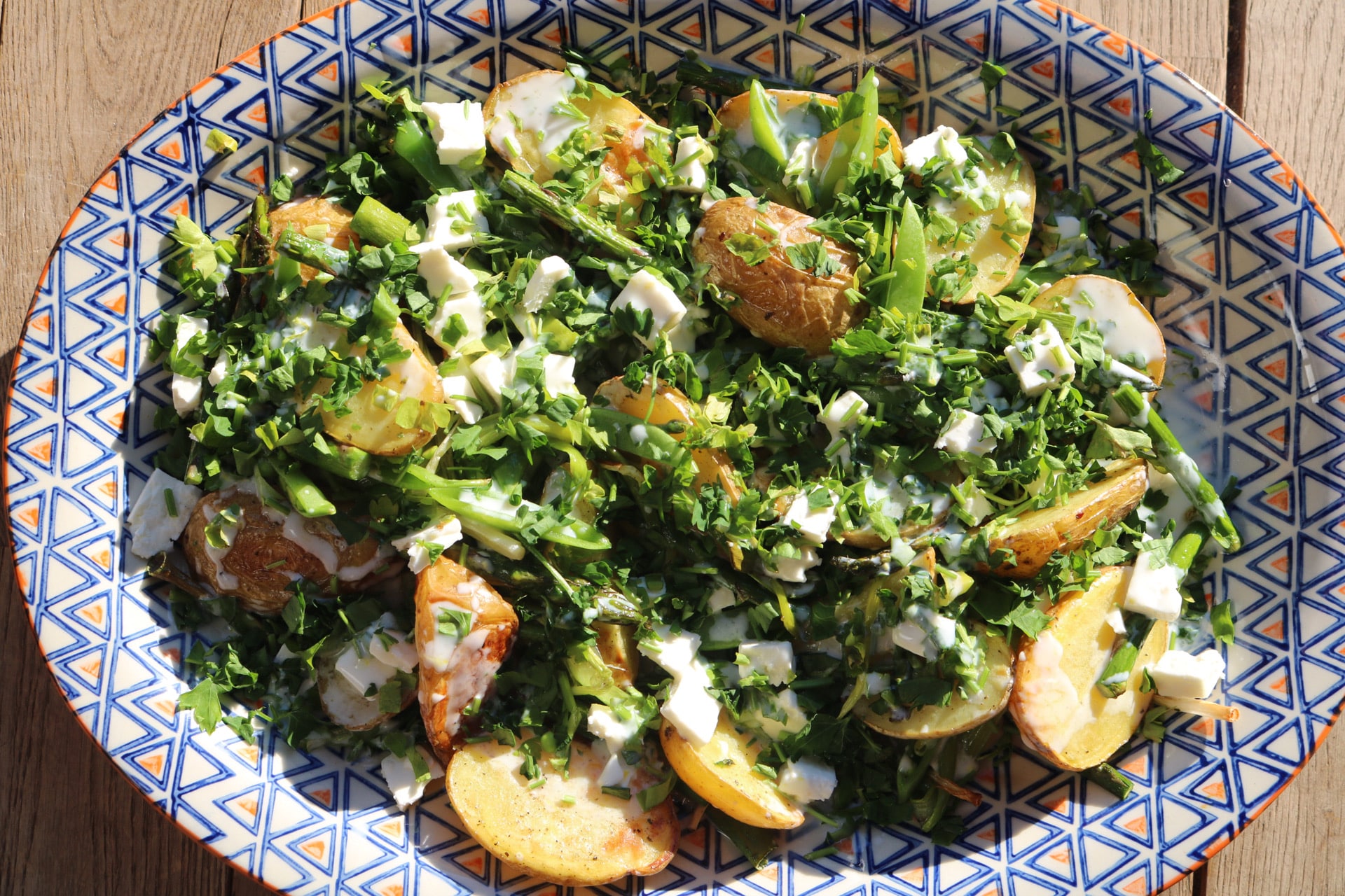 Spring potato salad on large blue, white and orange patterned serving platter
