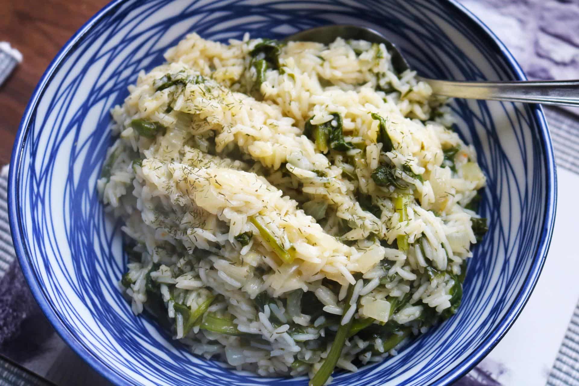 Close up of rice in a blue and white bowl with serving spoon