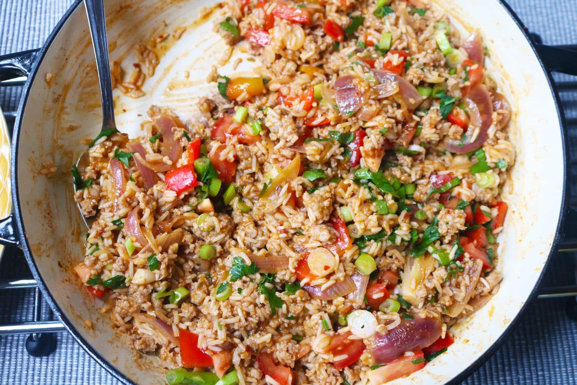 Spicy sausage rice in large casserole with serving spoon