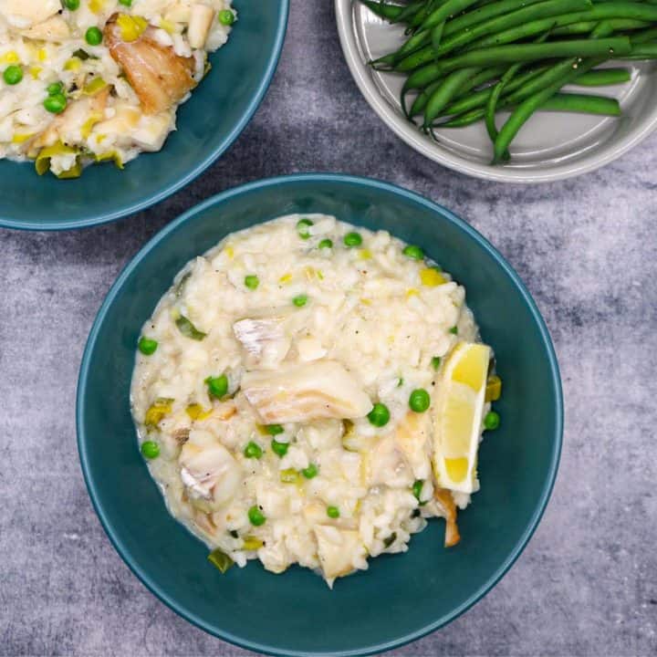 Smoked haddock risotto in a green bowls with wedge of lemon next to bowl of green beans