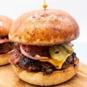 close up of steak and bacon burger in brioche bun on wooded board