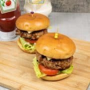 2 pork and chorizo burgers in brioche buns on a board with ketchup and mayo in the background