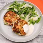 Salmon prawn and pea fish cakes on grey plate with rocket and parmesan salad