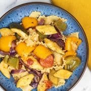 Roast mediterranean vegetable mafalde in a blue pasta bowl with mustard napkin on the side