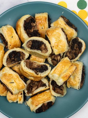 Duck and black pudding sausage rolls on a teal dinner plate with spotty napkins on the side
