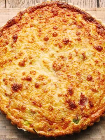 Overhead photo of ham and leek quiche on wooden chopping board