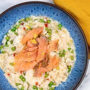 Smoked salmon and prawn risotto in a blue patterned bowl with mustard napkin on the side.
