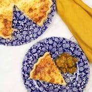 Ham and leek quiche on blue and white patterned plates - one with a slice and piccalilli, with a mustard napkin on the side.