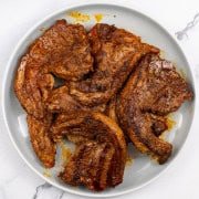 BBQ merguez lamb chops on a grey plate.