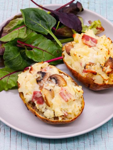 Bacon and mushroom baked potato on grey plate with salad leaves