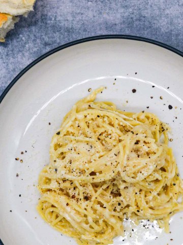 cacio e pepe in bowl with bread in background