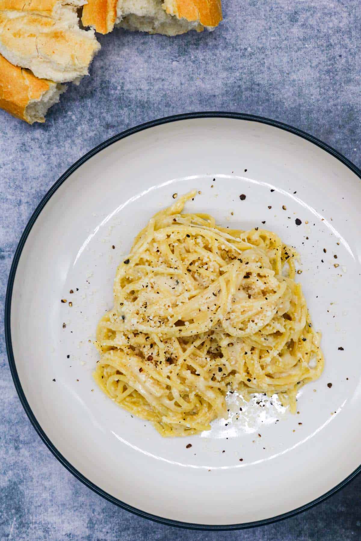 cacio e pepe in bowl with bread in background