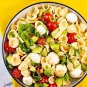 Caprese pasta salad in a black and cream bowl.