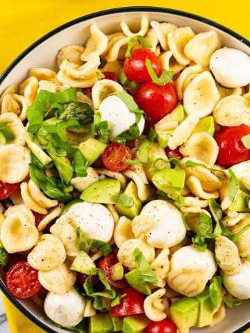 Caprese pasta salad in a black and cream bowl.