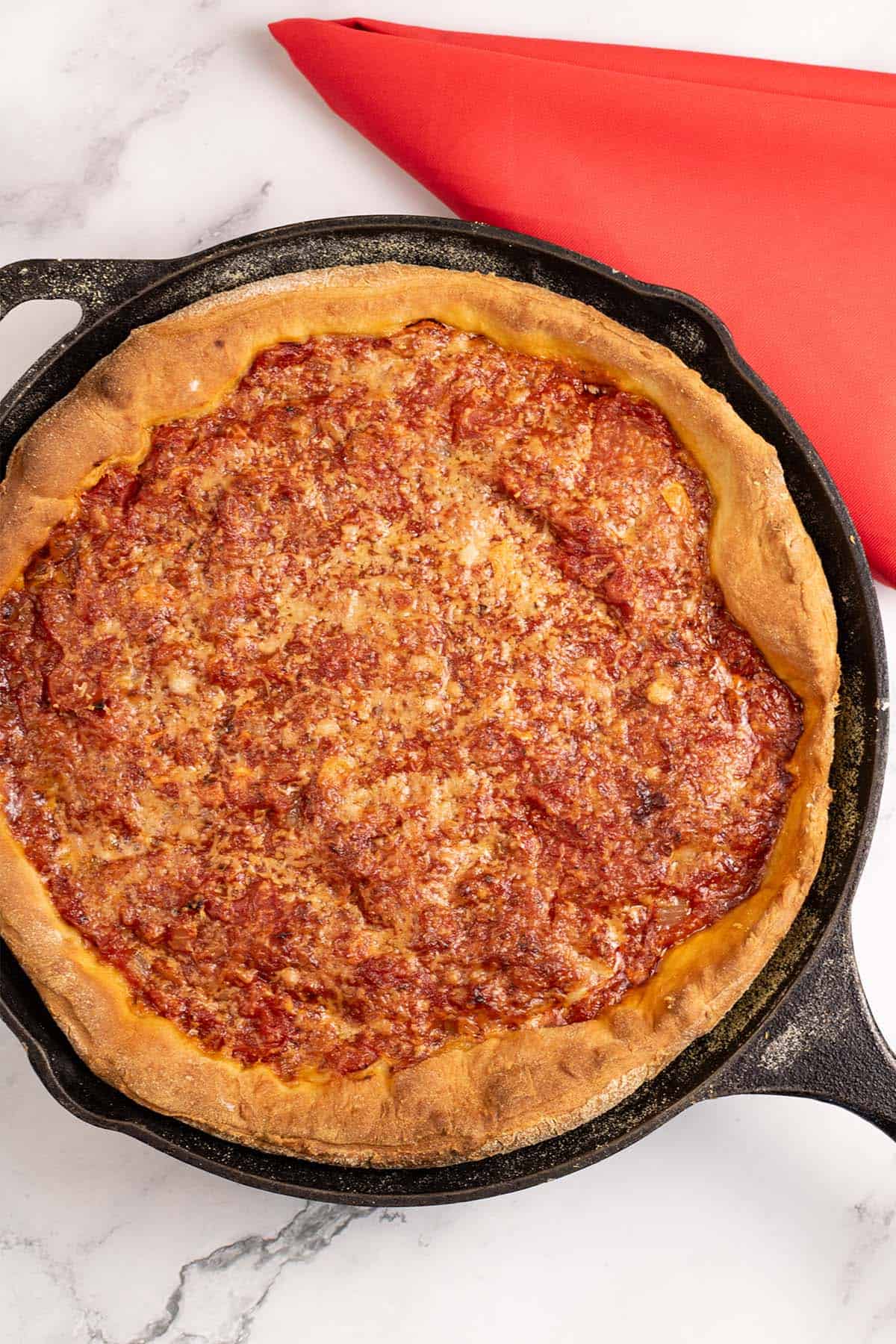 Chicago deep pan pizza in a black skillet with a red napkin on the side.