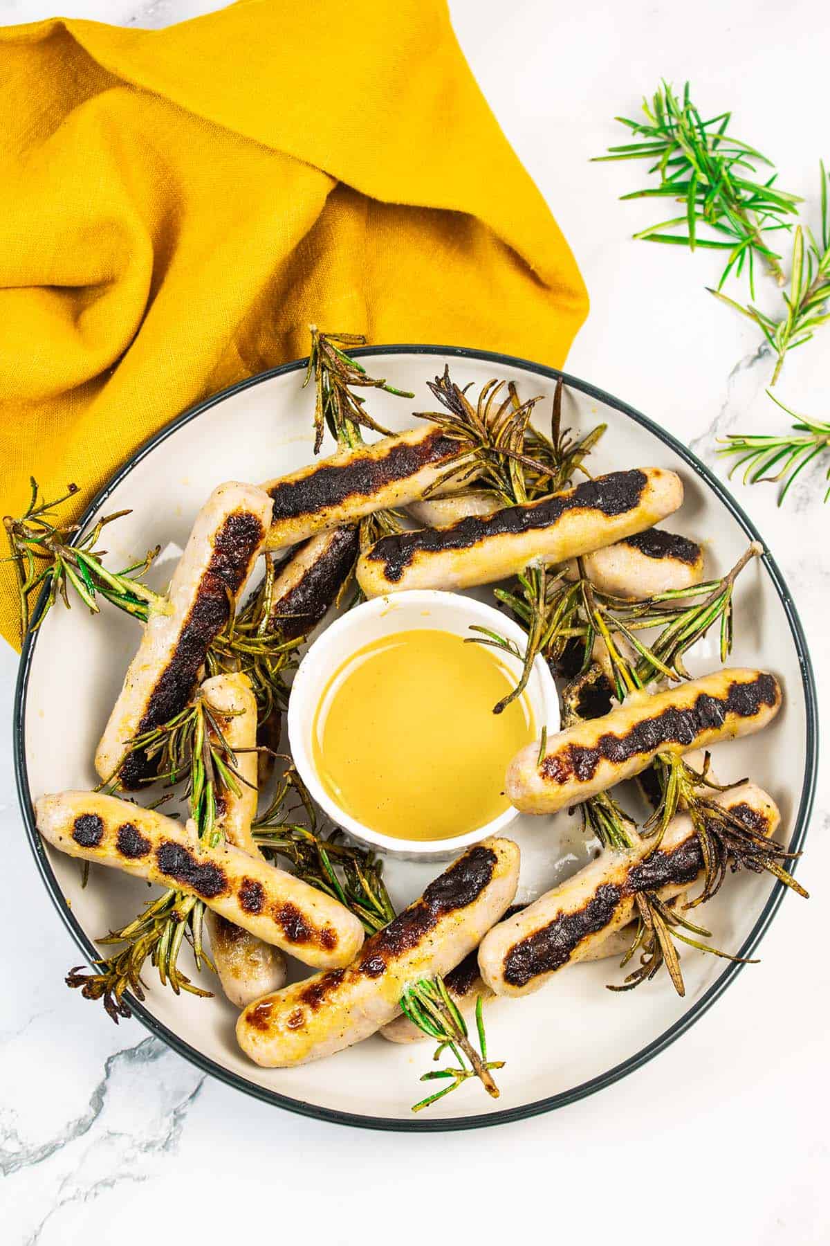 Chipolata rosemary skewers in a bowl with honey mustard dressing