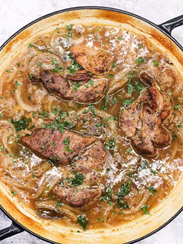 Cider braised pork steaks with onions in a large round casserole