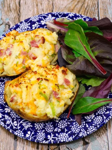 leek and bacon baked potato on blue and white plate with salad leaves