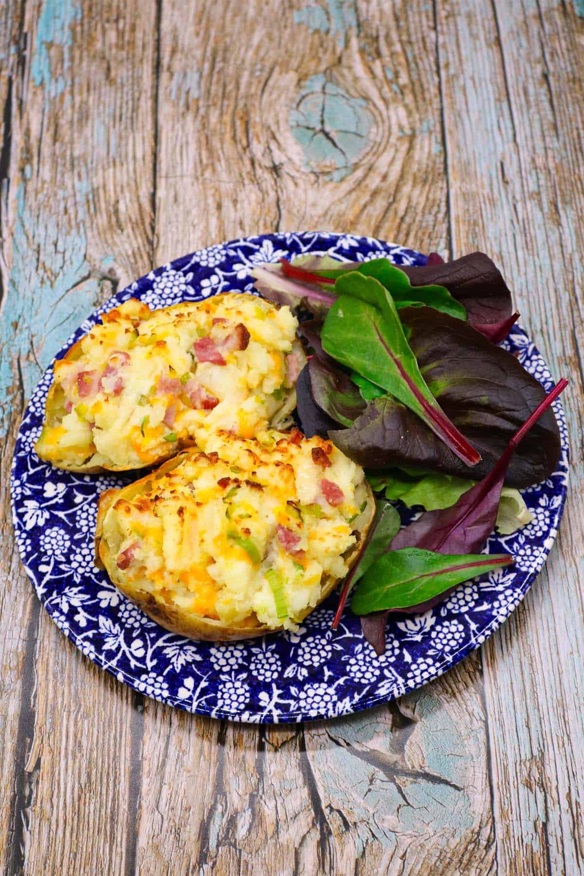 leek and bacon baked potato on blue and white plate with salad leaves