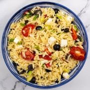 Orzo salad with feta in a blue and white striped bowl.