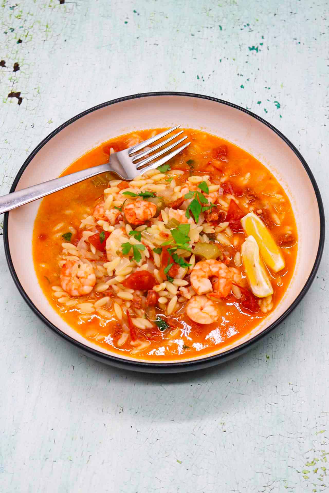 Slow cooker prawn and chorizo paella in bowl with lemon wedges and a fork