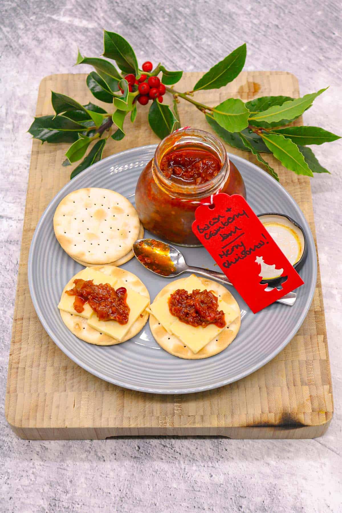 Plate with crackers spread with bacon and cranberry jam and cheese with jar