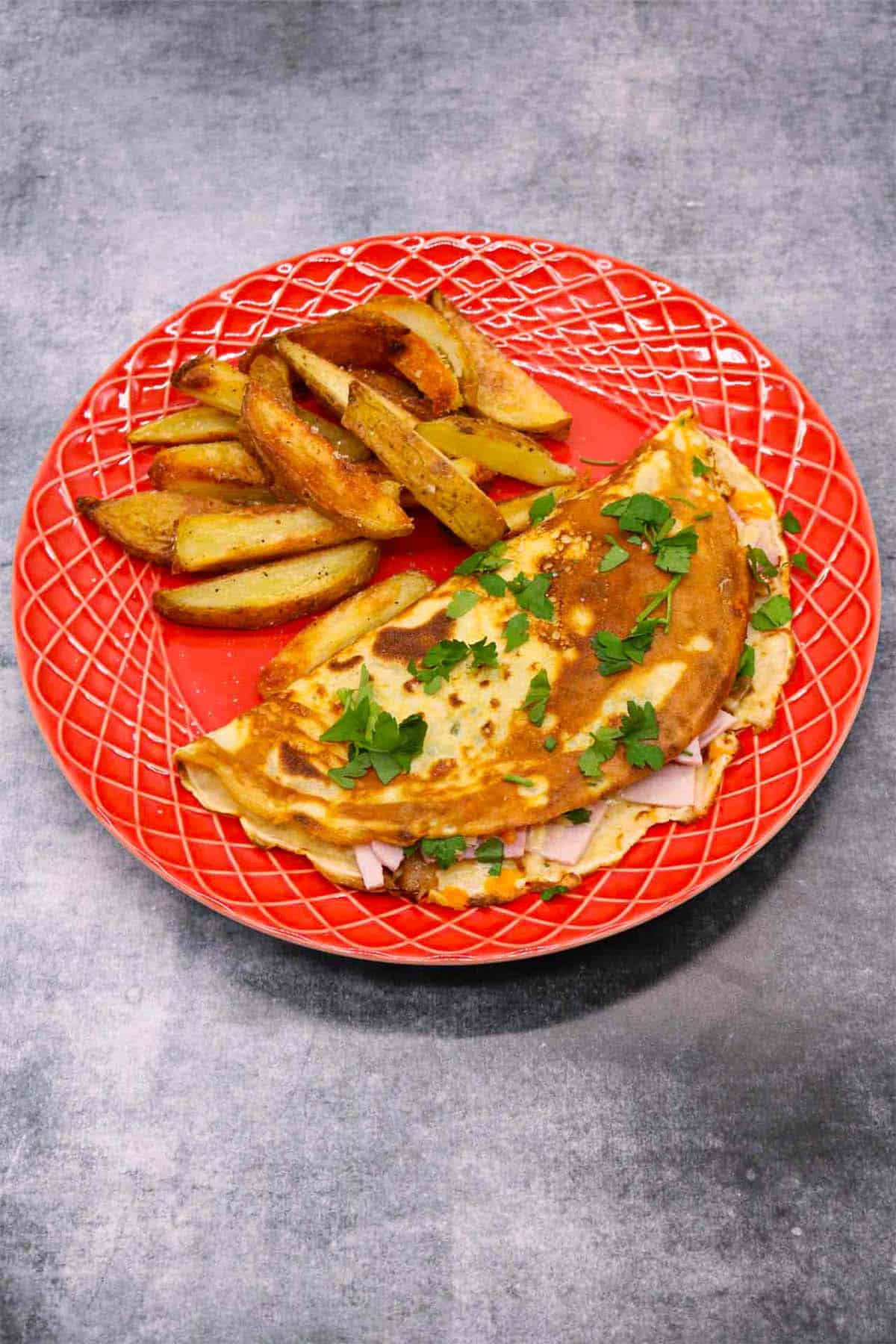 Cheese and ham pancake on red plate with chips