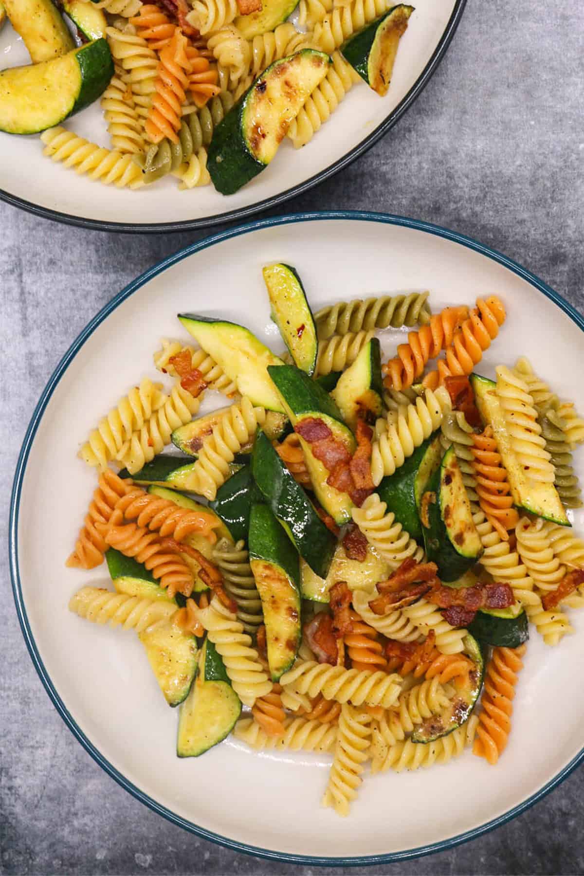 Two bowls of chargrilled courgette and smoked bacon pasta.
