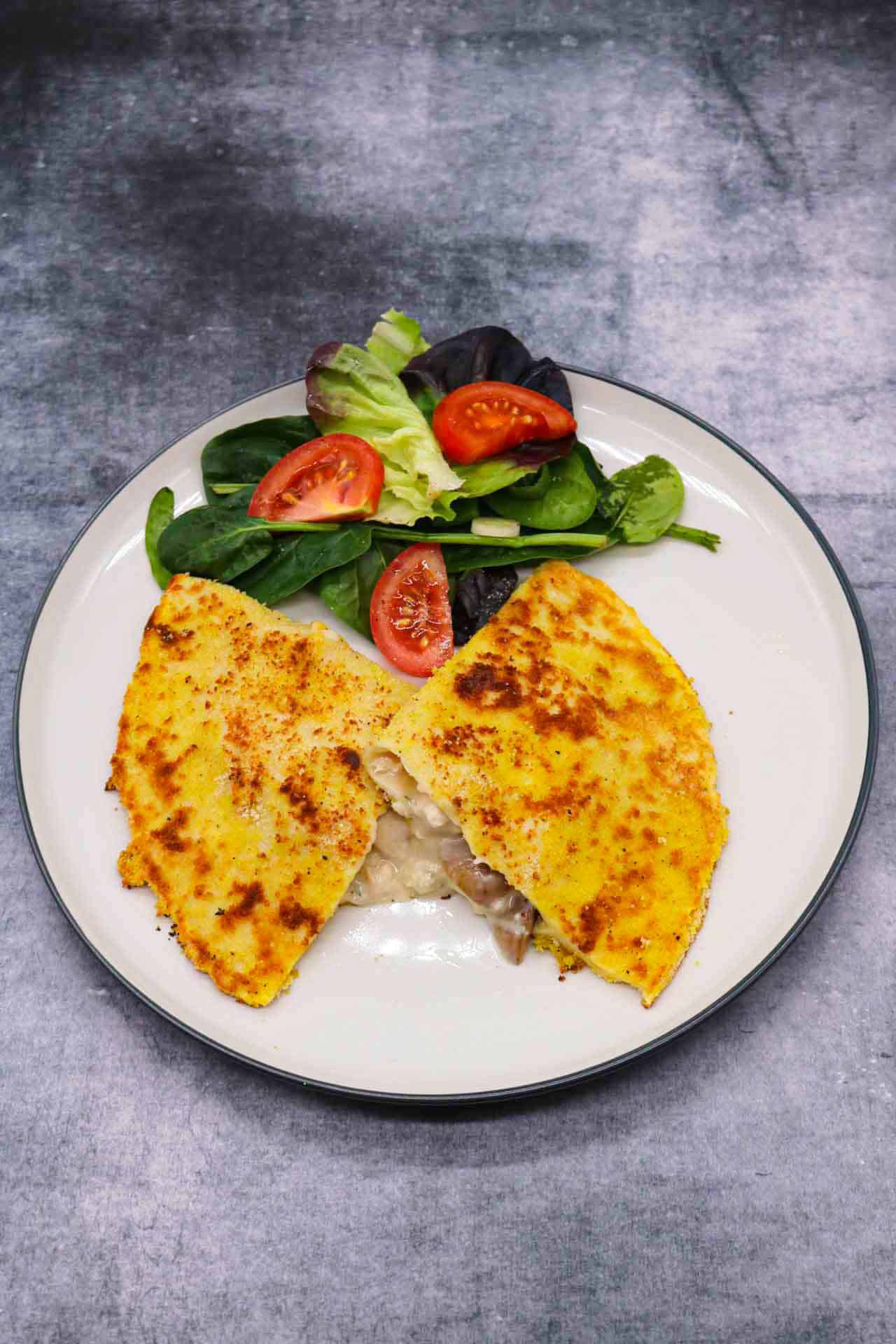 Creamy chicken and mushroom crispy pancake on plate with salad leaves